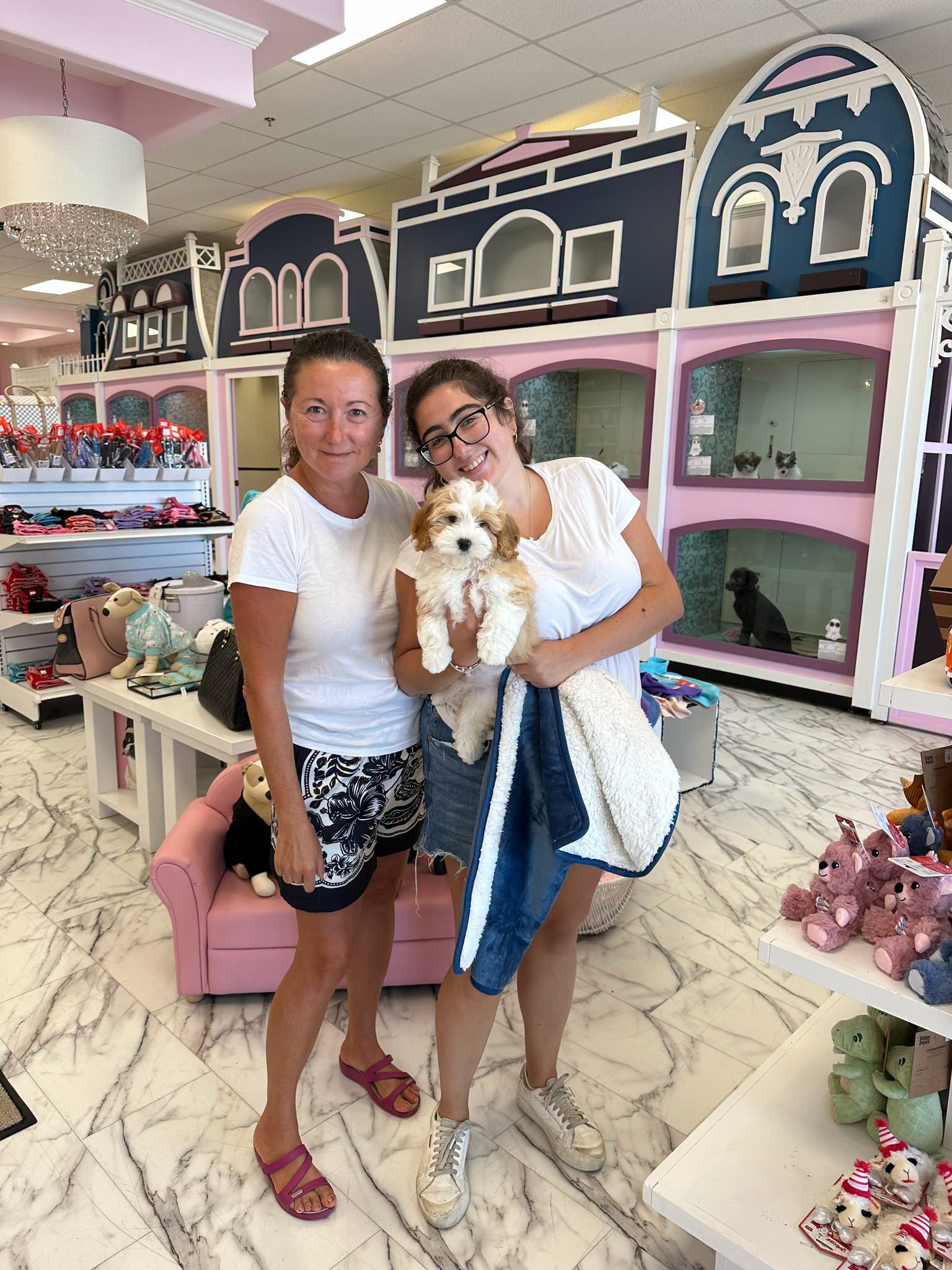 Two people with a white-and-tan puppy inside the pink Furrylicious boutique